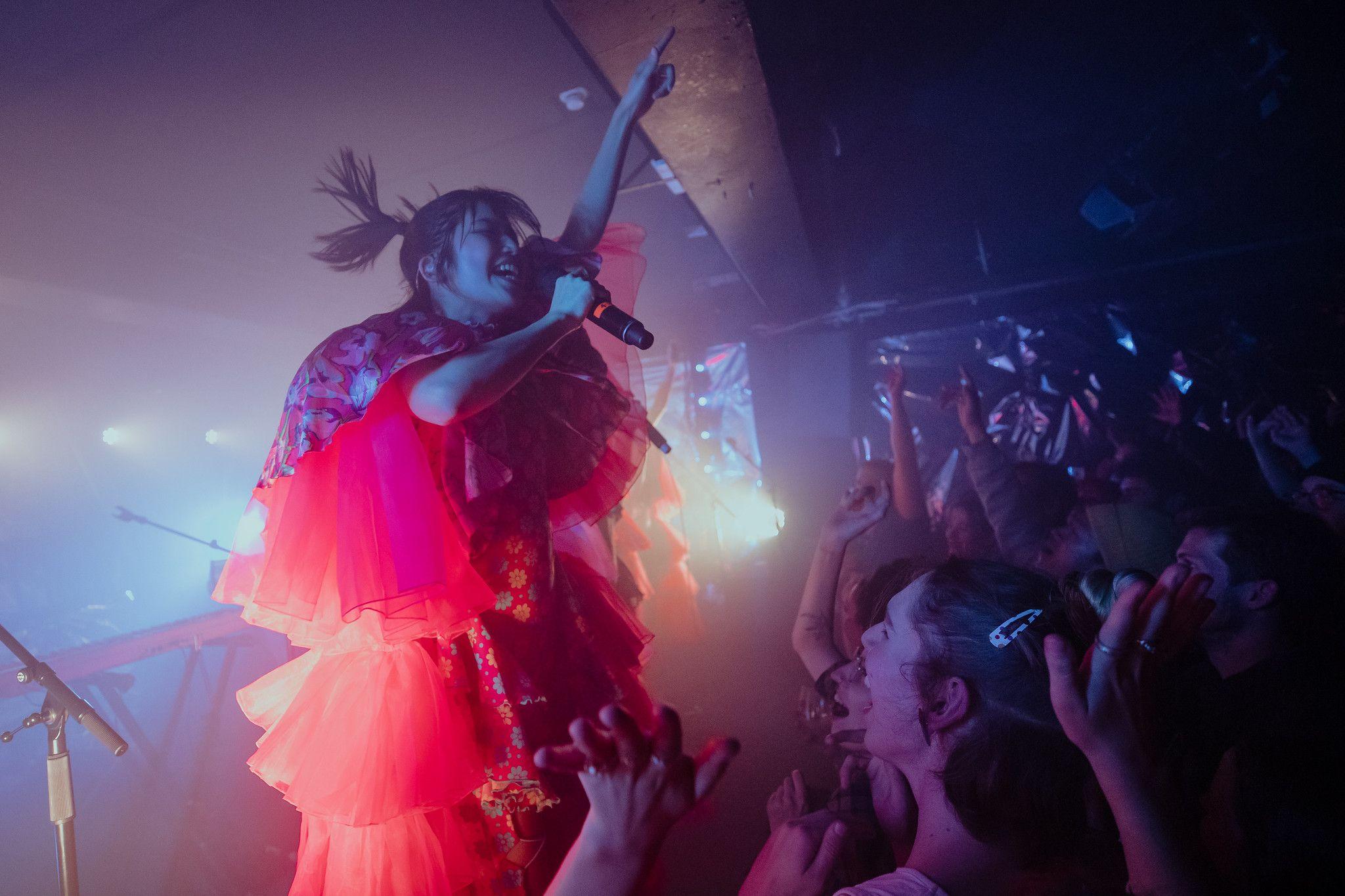 A person signs into a microphone on stage, perfomring at Altar.